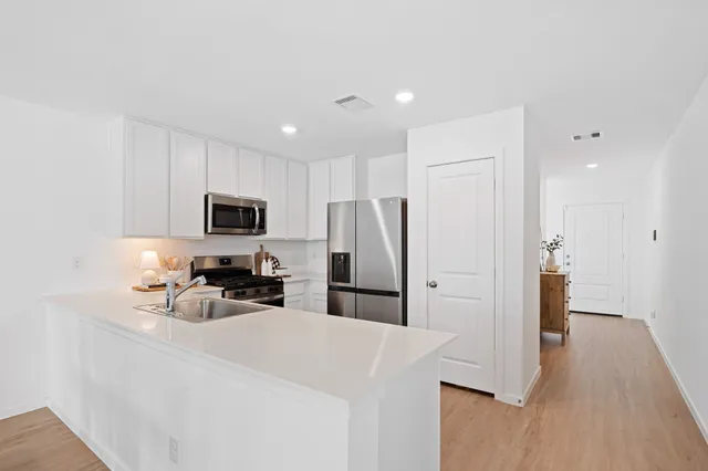 a kitchen with stainless steel appliances a refrigerator a stove a sink and white cabinets