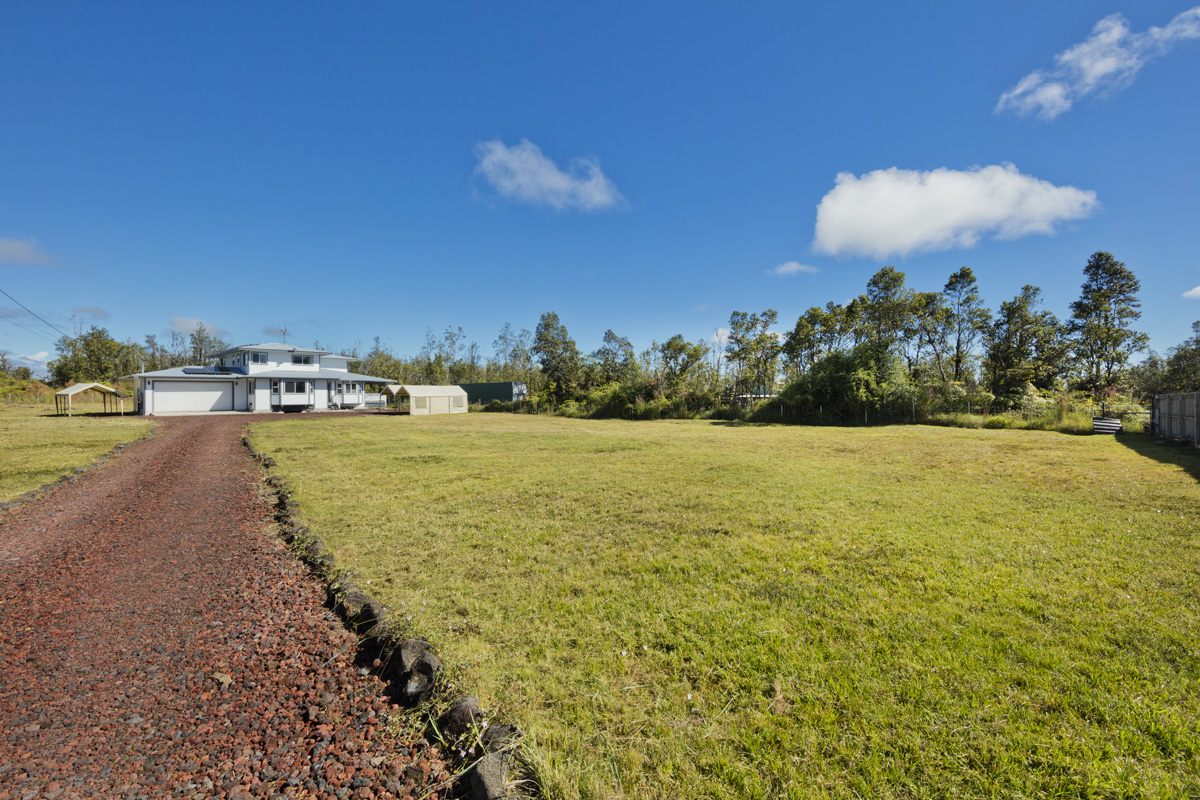 a view of a lake with lawn chairs and large trees