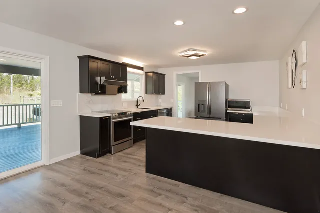 a kitchen with stainless steel appliances kitchen island granite countertop a refrigerator and a stove top oven