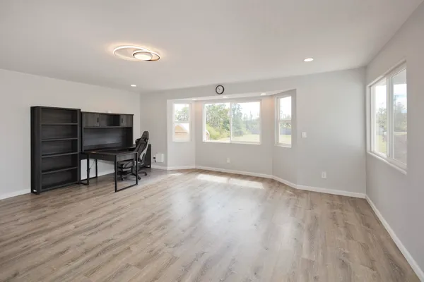 an empty room with windows wooden table and chair