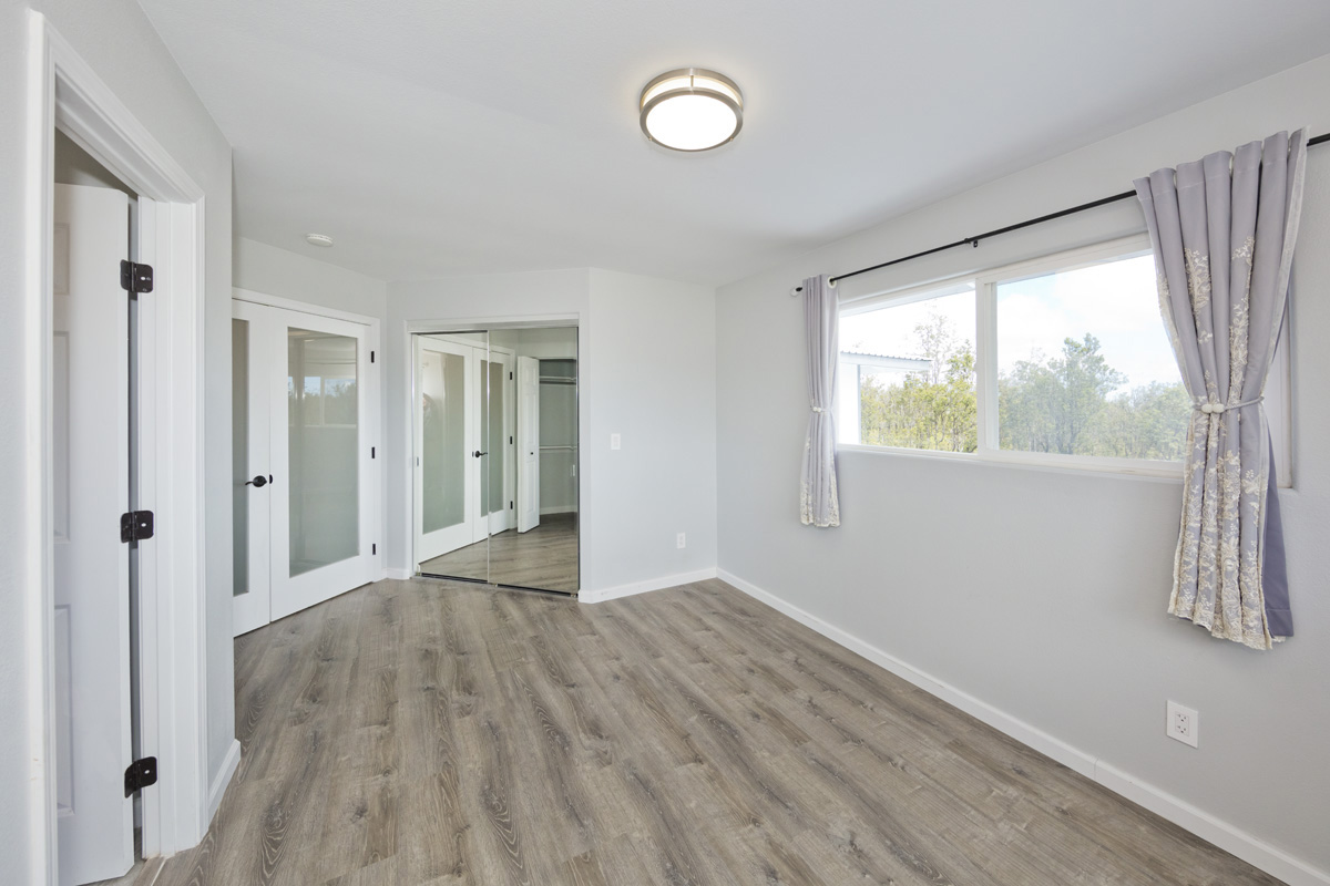 11-2420 Ohialani Road Mountain View, HI 96771 - Photo 19 of 30 a view of an empty room with wooden floor and a window