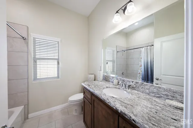 a bathroom with a granite countertop sink a toilet and a mirror