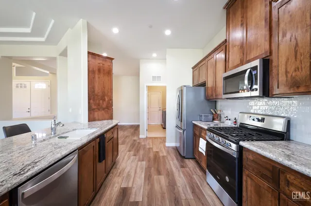 a kitchen with stainless steel appliances granite countertop wooden cabinets a stove top oven a sink and dishwasher