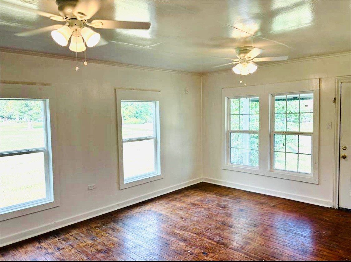 1314 Sabine Street Orange, TX 77630 - Photo 3 of 9 an empty room with wooden floor fan and windows