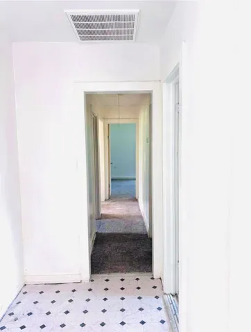 a view of a hallway view with wooden floor and a white cabinet