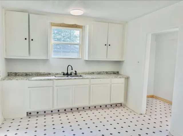 a kitchen with granite countertop white cabinets and black appliances