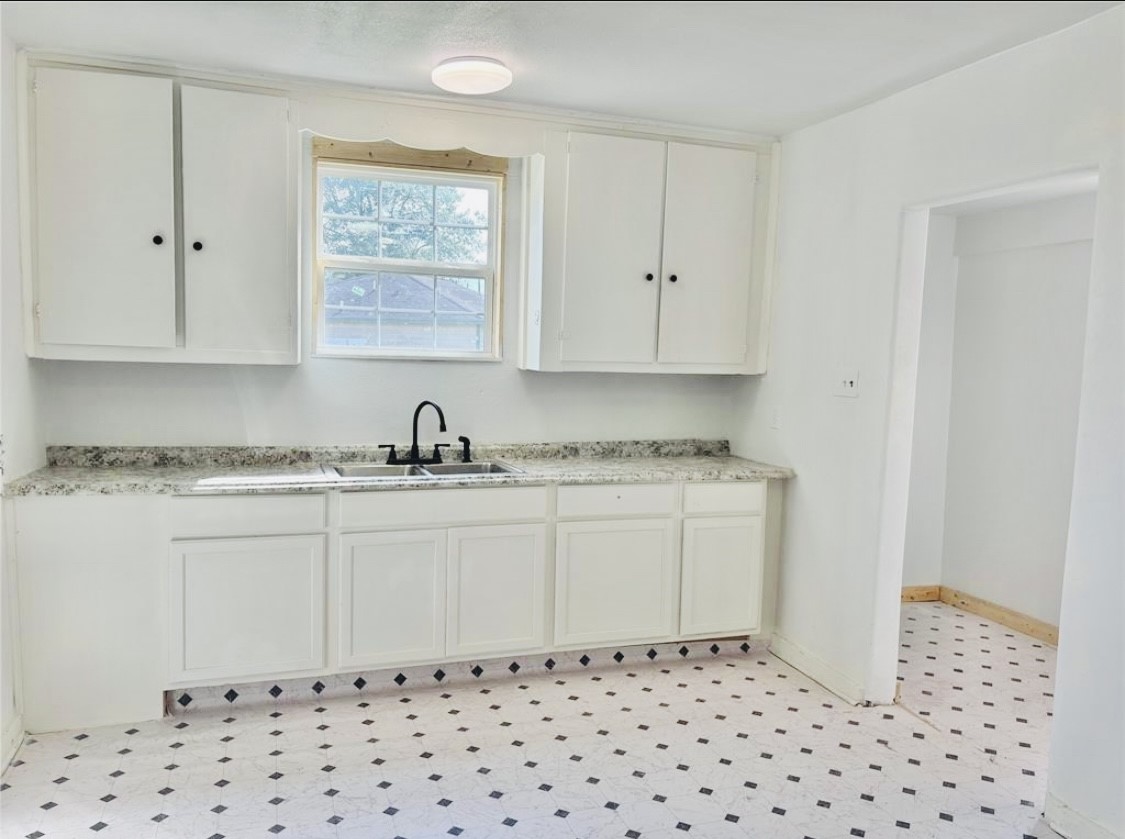 1314 Sabine Street Orange, TX 77630 - Photo 6 of 9 a kitchen with granite countertop white cabinets and black appliances