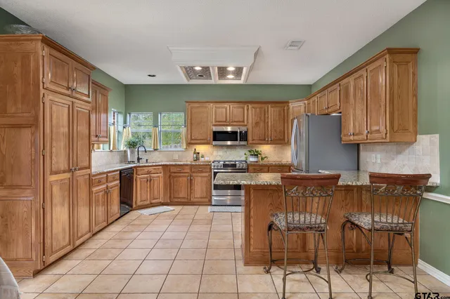 a kitchen with stainless steel appliances granite countertop a stove top oven a sink dishwasher and a refrigerator