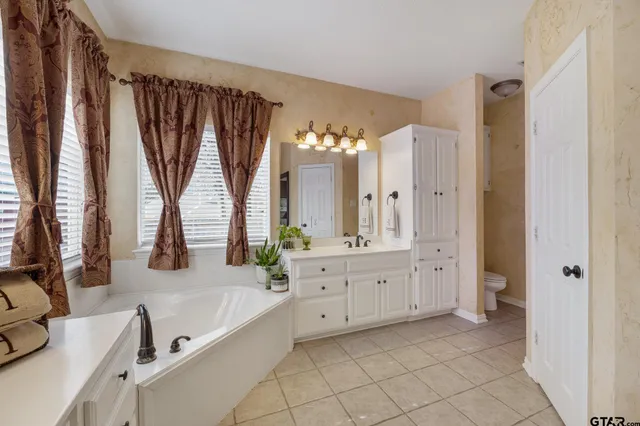 a large bathroom with a double vanity sink a large mirror and a bathtub