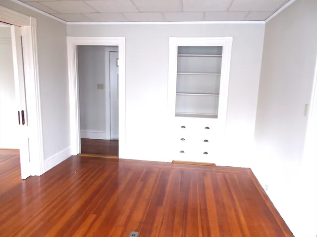 an empty room with wooden floor and cabinet