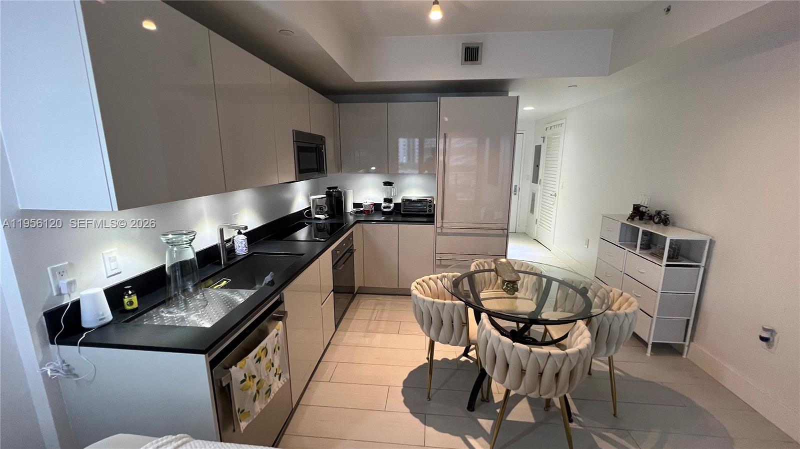 1010 Brickell Avenue, Unit 1510 Miami, FL 33131 - Photo 4 of 32 a kitchen with stainless steel appliances kitchen island granite countertop a sink a stove a table and chairs