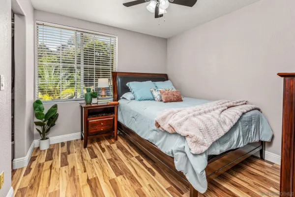 a bedroom with a bed table flowerpot and a window