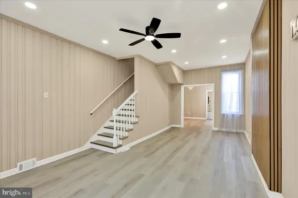 a view of an empty room with wooden floor and stairs