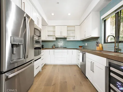 a large kitchen with stainless steel appliances granite countertop a stove a sink and white cabinets with wooden floor