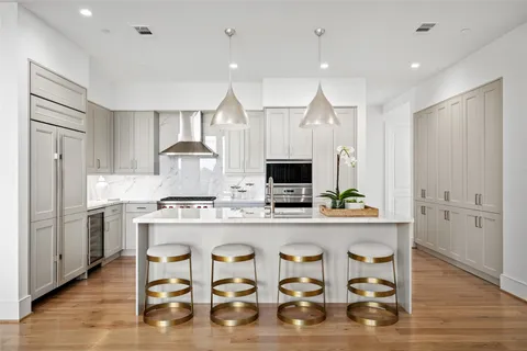 a kitchen with kitchen island granite countertop a sink a stove a refrigerator cabinets and dining table