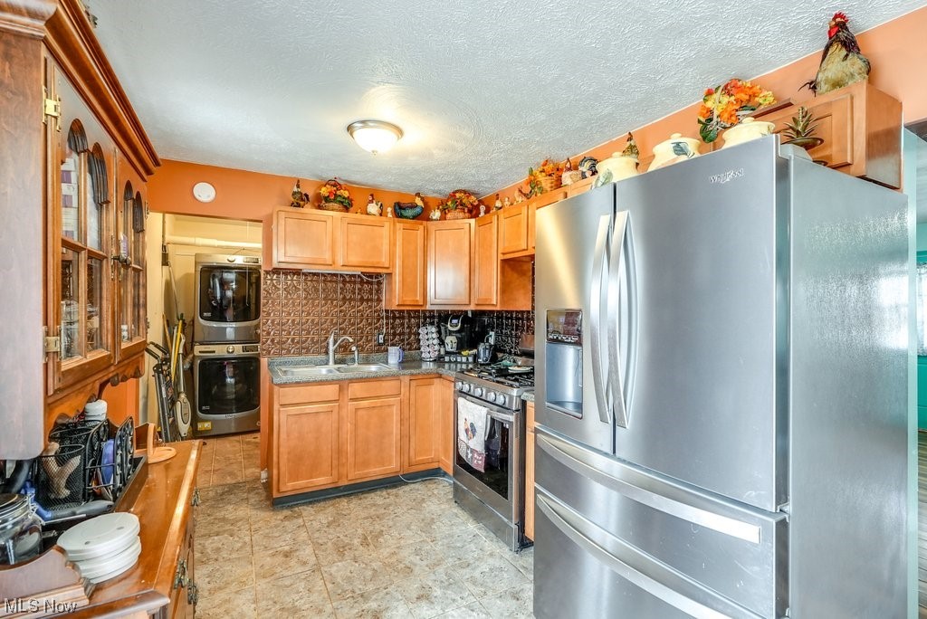 3658 Duffield Road Kent, OH 44240 - Photo 17 of 21 Kitchen featuring stainless steel appliances, stacked washer and dryer, light tile floors, backsplash, and sink