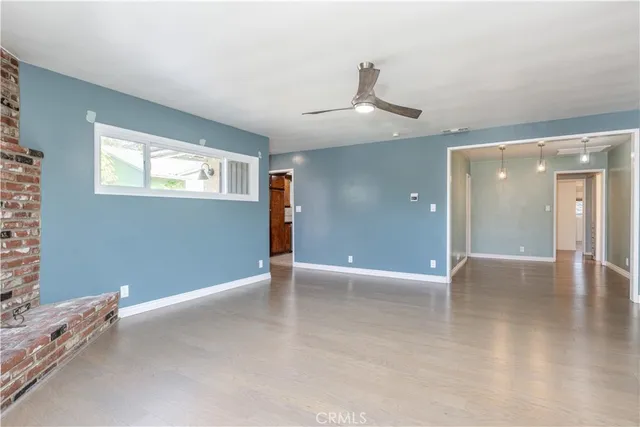 an empty room with wooden floor cabinet and windows