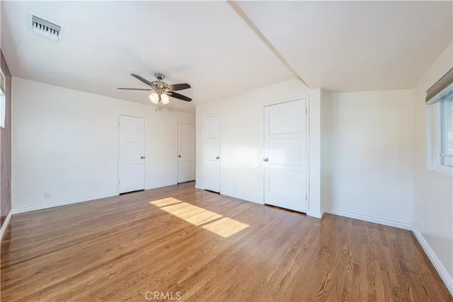 a view of a room with wooden floor and a ceiling fan