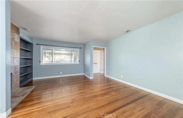 a view of an empty room with a window and wooden floor