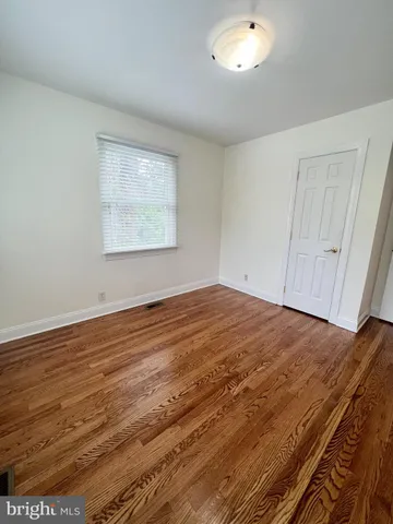 a view of empty room with window and wooden floor