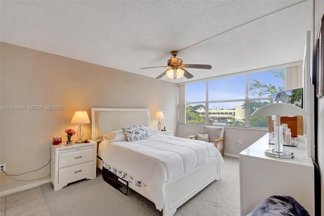 a bedroom with a bed a large window with table and chairs