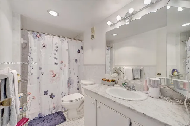 a bathroom with a granite countertop sink mirror vanity and toilet