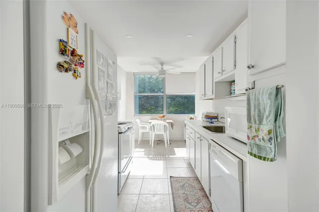 a kitchen that has a lot of white cabinets and couches