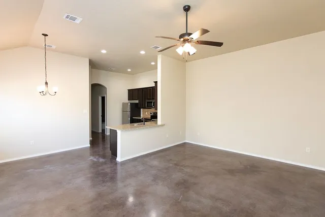 a view of an empty room with kitchen view