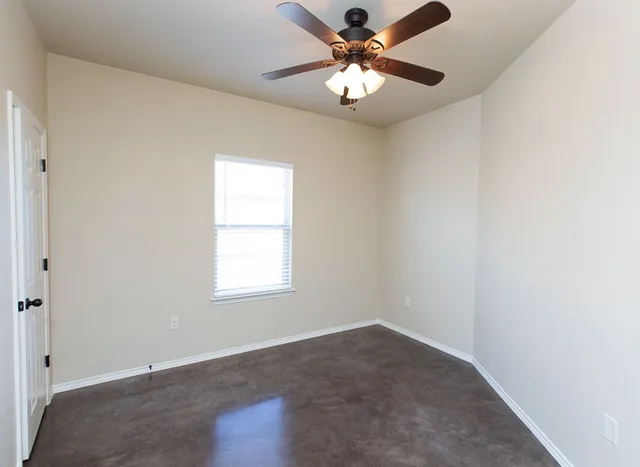 an empty room with a window and a fan