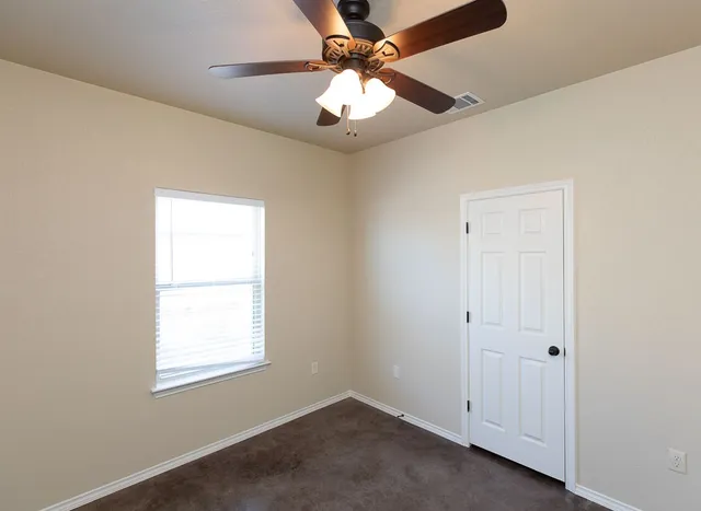 an empty room with a window and a fan