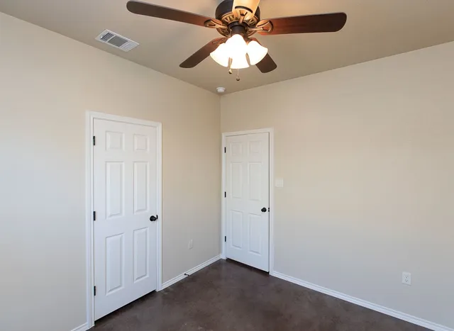 an empty room with a chandelier fan and closet area