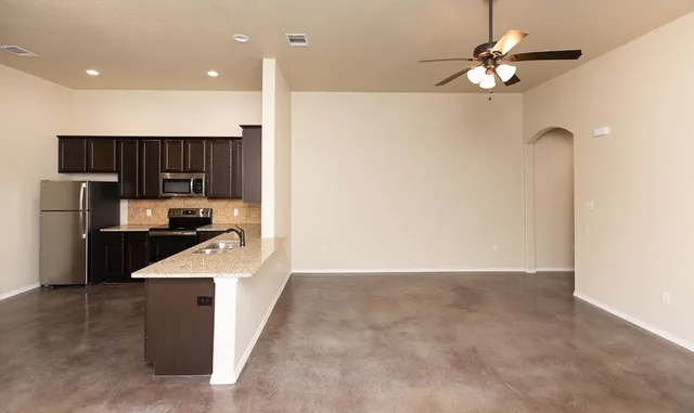 a kitchen with kitchen island a counter top space appliances and a ceiling fan