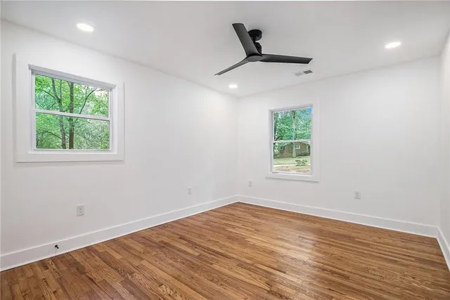 a view of a room with wooden floor a ceiling fan and windows