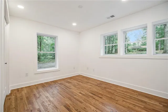 an empty room with wooden floor and windows