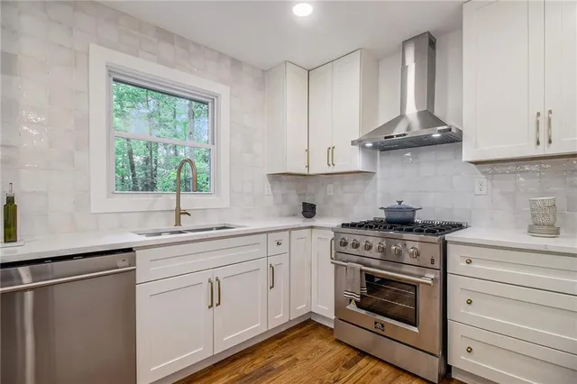 a kitchen with stainless steel appliances granite countertop a sink a stove and cabinets