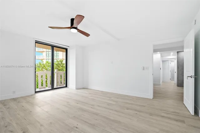 a view of empty room with wooden floor and ceiling fan
