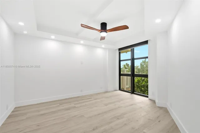 a view of empty room with wooden floor and ceiling fan