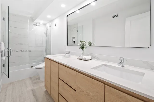 a bathroom with a shower sink vanity and mirror