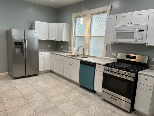 8153 South Exchange Avenue Chicago, IL 60617 - Photo 4 of 11 a kitchen with cabinets stainless steel appliances and a sink