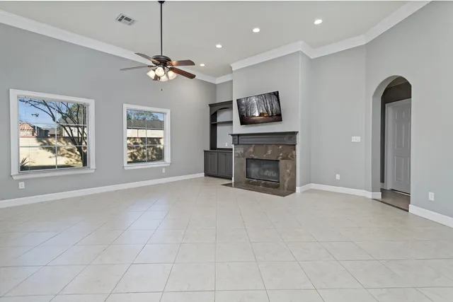 a view of a livingroom with a fireplace a ceiling fan and windows