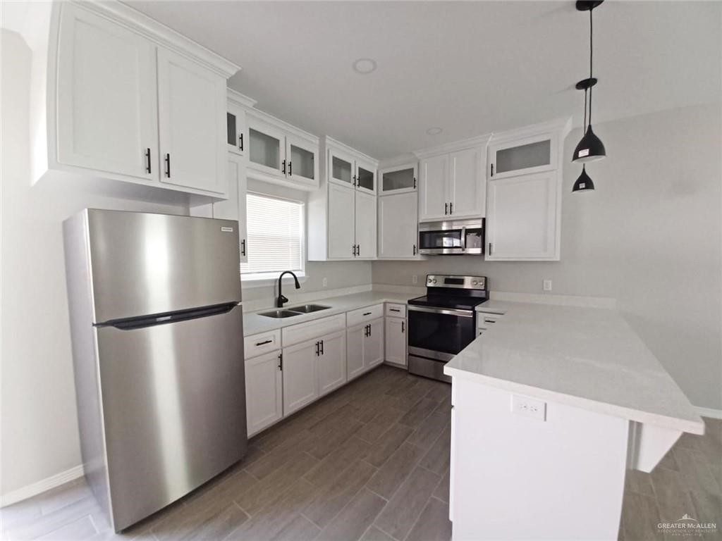 1506 Playa Drive, Unit 1 Weslaco, TX 78596 - Photo 2 of 9 a kitchen with a refrigerator a stove top oven a white cabinets and wooden floor