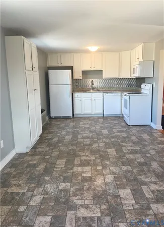 a kitchen with a refrigerator a stove top oven and white cabinets