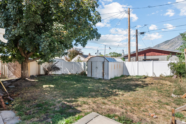 31 B Street Springville, UT 84663 - Photo 24 of 31 Expansive grassy yard area, mature tree providing natural shade, white privacy fencing, storage shed, and mountain range in the background