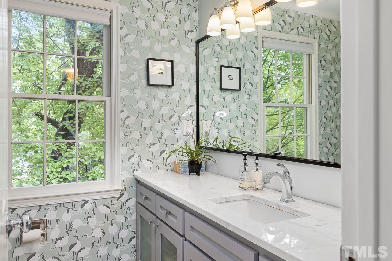 7309 Glendower Road Raleigh, NC 27613 - Photo 10 of 19 a bathroom with a granite countertop sink a mirror and a window