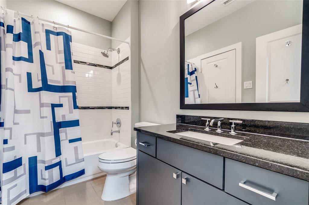 7912 Hanover Street Dallas, TX 75225 - Photo 10 of 29 Bathroom featuring a white subway tile shower surround with decorative accent bands, a white bathtub, and a built-in vanity with a dark stone countertop and undermount sink