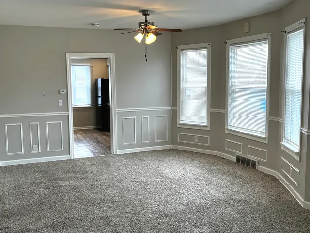 an empty room with windows and fan