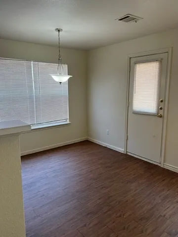 an empty room with wooden floor fan and window