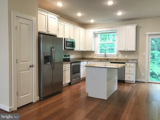 a kitchen with kitchen island granite countertop a sink cabinets and stainless steel appliances