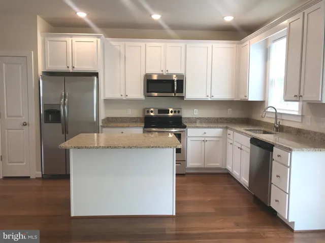 a kitchen with kitchen island granite countertop a sink a counter top space stainless steel appliances and cabinets