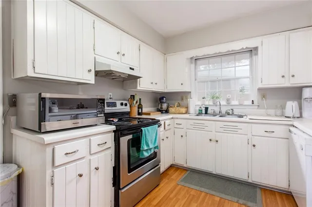 a kitchen with granite countertop white cabinets sink and stainless steel appliances